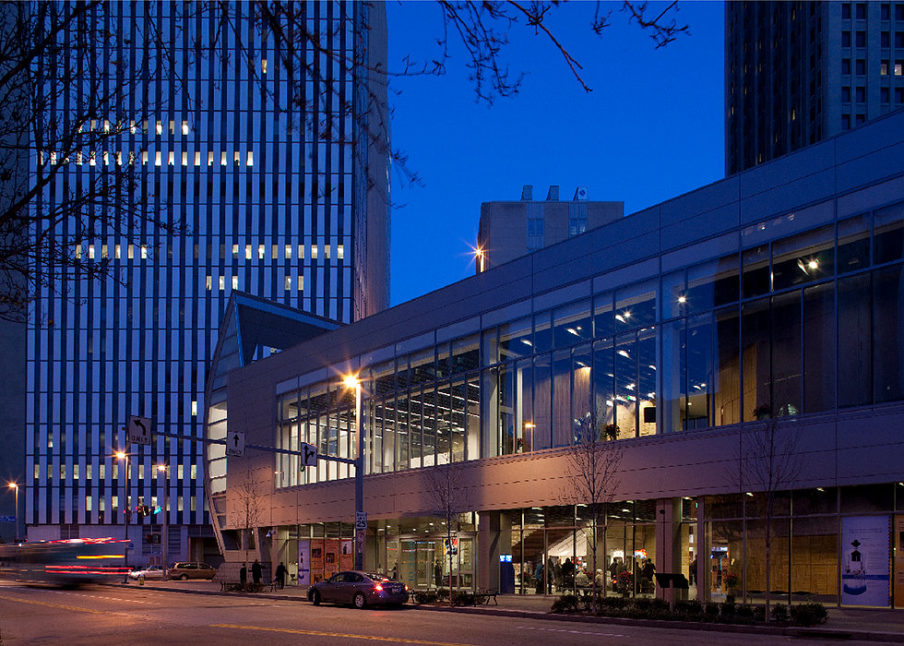 The Center at Night: The building's large windows open it up to the street, the glints of light from inside the center draw the pedestrian's attention and the gathering crowd inside suggests there's on-going programming occurring.